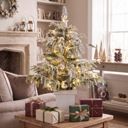 3ft flocked Christmas tree on a coffee table with wrapped gifts in a living room