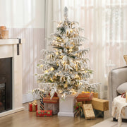 Lit 4ft flocked Christmas tree in a living room with gifts by the fireplace