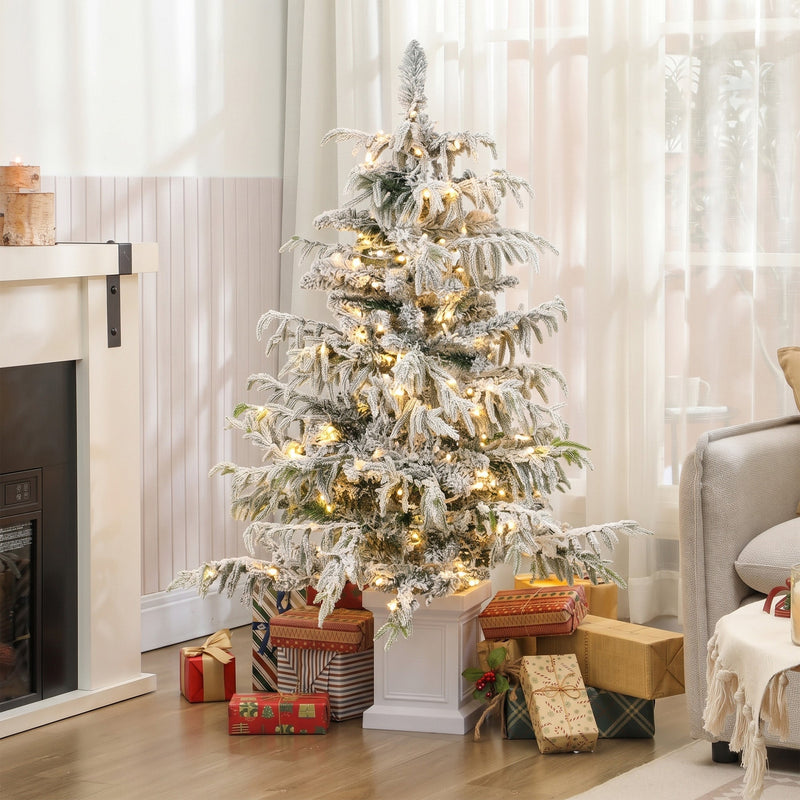 Lit 4ft flocked Christmas tree in a living room with gifts by the fireplace