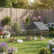 Rabbits inside the metal run in a garden with flower beds and a wooden fence