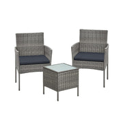 Grey rattan garden set with two cushioned armchairs and a square glass top table on white