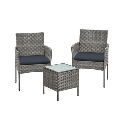Grey rattan garden set with two cushioned armchairs and a square glass top table on white