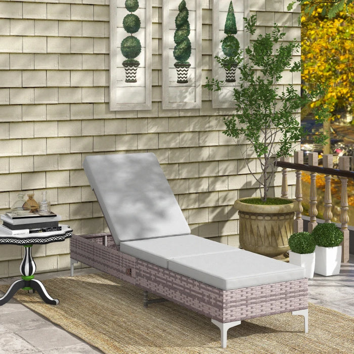 Image of a reclining rattan sun lounger with a light grey cushion