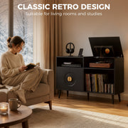 Woman reading in an armchair beside a black record player stand in a living room