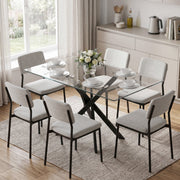 Glass dining table set for a meal with grey upholstered chairs in a bright kitchen