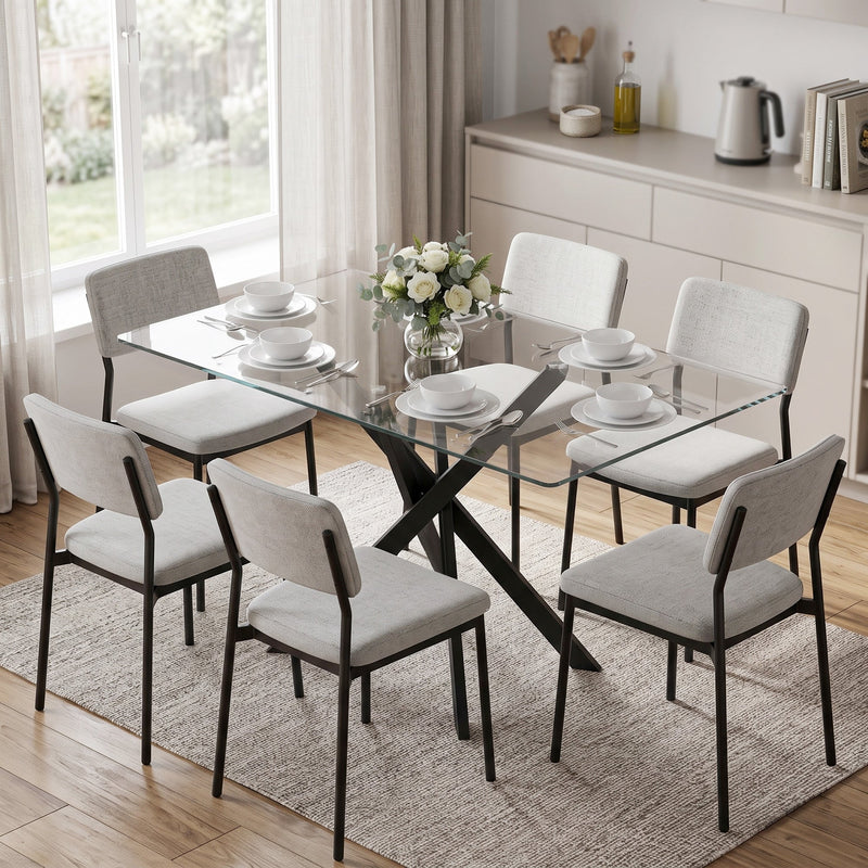 Glass dining table set for a meal with grey upholstered chairs in a bright kitchen