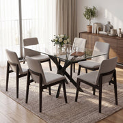 Glass dining table with grey fabric chairs on a rug