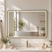 Black-framed LED bathroom mirror lit above a vanity with a freestanding bath reflected in it