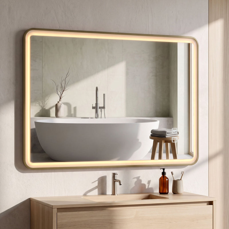 Gold LED bathroom mirror mounted horizontally above a wooden vanity with a bath in the reflection