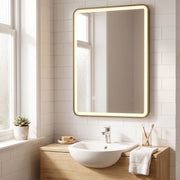 Gold LED bathroom mirror mounted vertically above a small basin and wooden cabinet