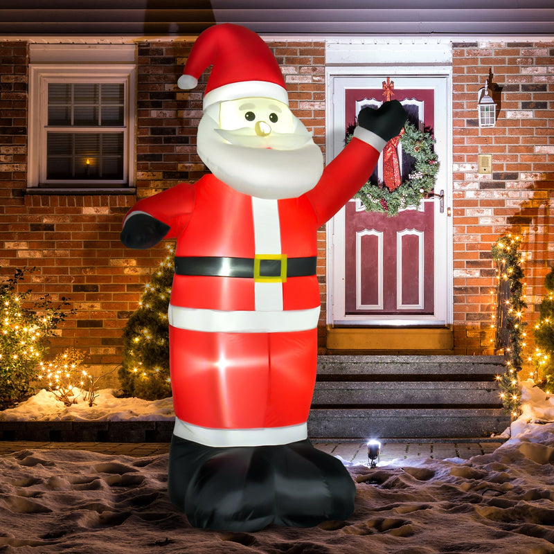 Inflatable Santa waving in front of a brick house with a wreathed door, a lit tree and snow