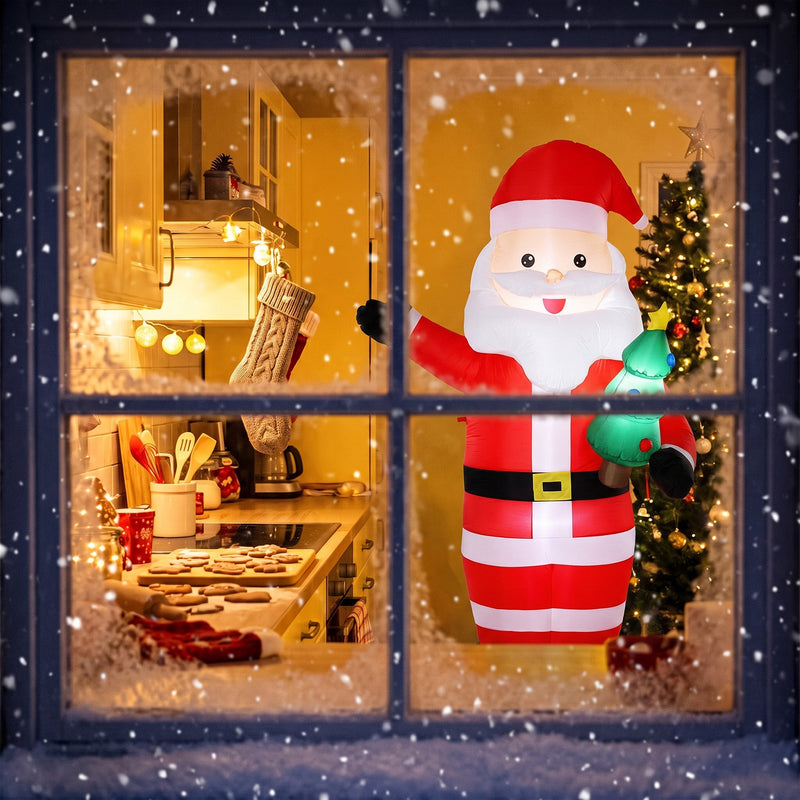 Lit Santa holding a tree seen through a snowy window