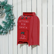 Red Christmas postbox mounted on a white wooden fence next to a wreath