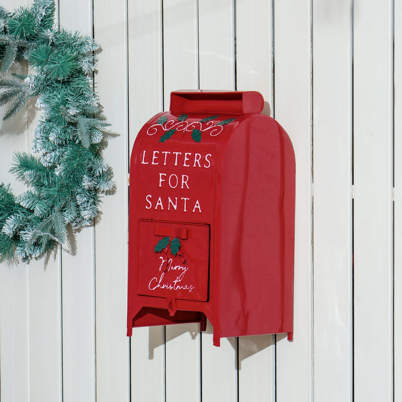 Red Christmas postbox mounted on a white wooden fence next to a wreath