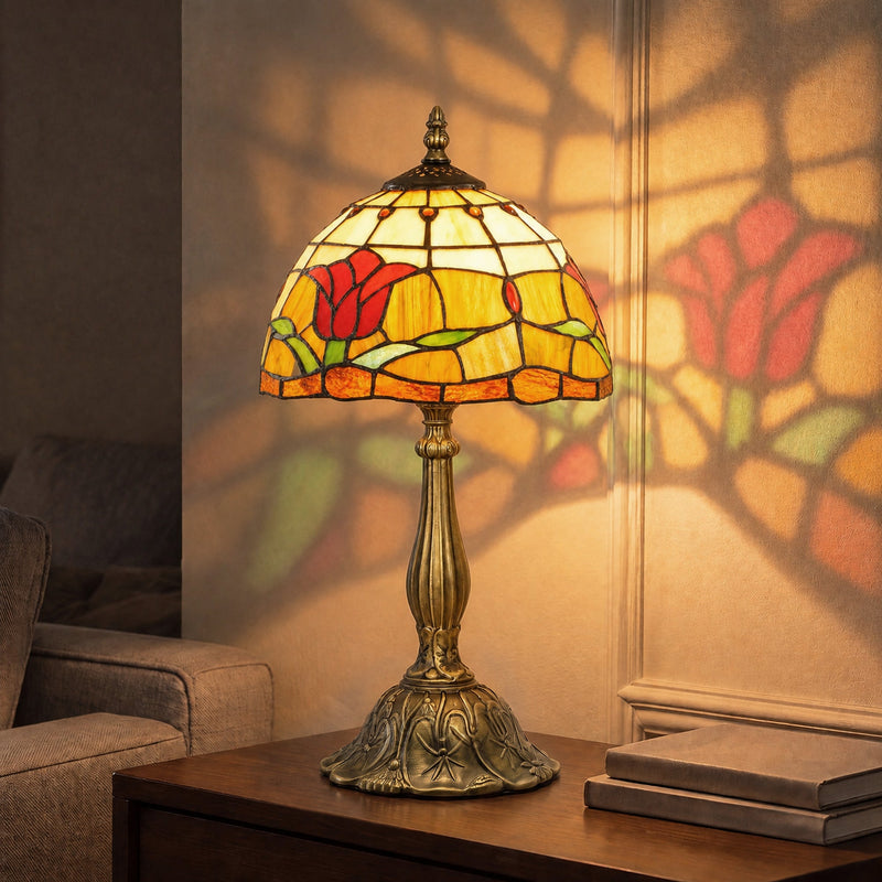 Lit stained glass table lamp casting patterned shadows on the wall beside books