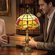 Man holding a wrapped gift beside the lit lamp on a wooden table