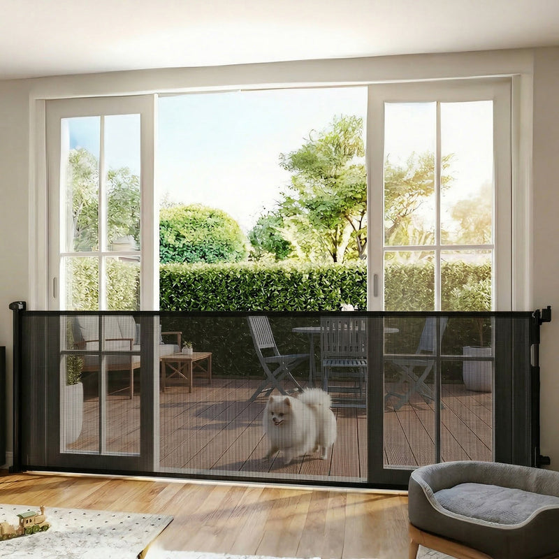 Black retractable dog gate across patio doors with a fluffy dog on the decking