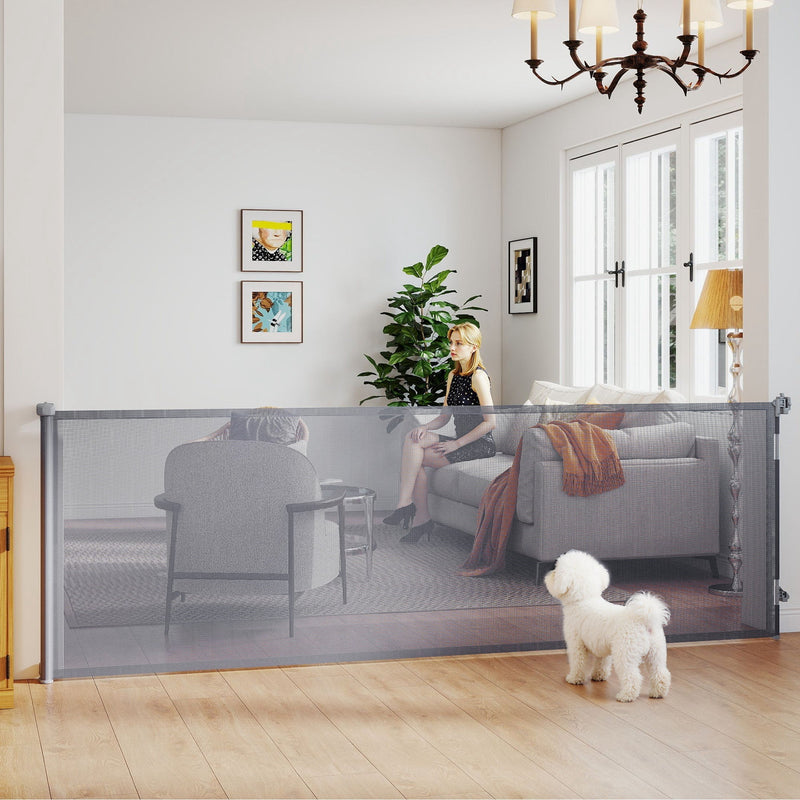 Grey retractable dog gate across a living room with a small white dog in front