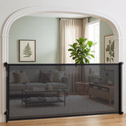 Black retractable dog gate across an arched doorway to a living room