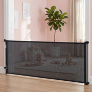Black mesh dog gate closed across a pink playroom with toys behind it