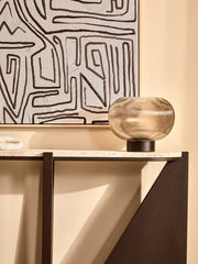 Smoked glass table lamp with black base styled on a shelf
