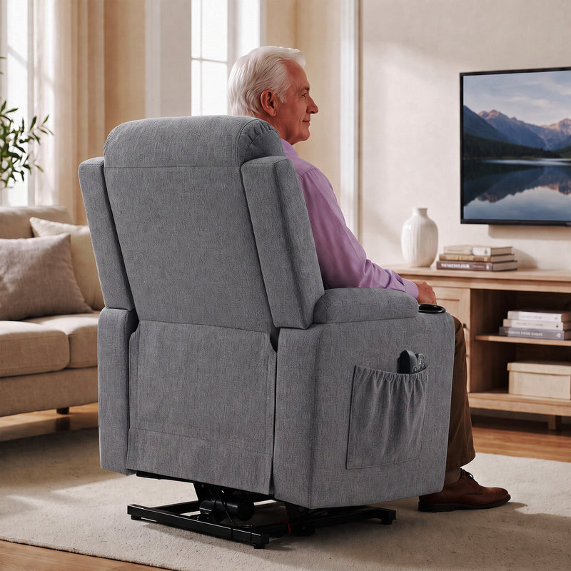 Rear view of the dark grey riser recliner with a side pocket, with a man seated watching TV