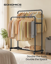 Ink black double rod clothes rack styled in a bedroom with hanging jumpers and a suitcase nearby