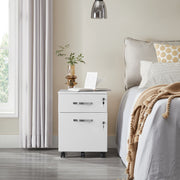 White 2-drawer file cabinet used as a bedside table next to a made bed and a plant