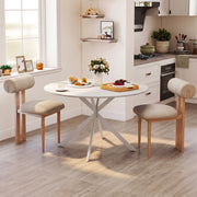 Round white table in a kitchen with two cushioned chairs and a bowl of flowers