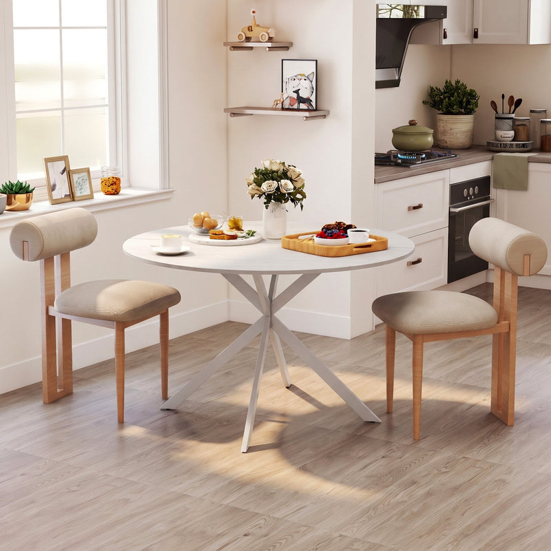 Round white table in a kitchen with two cushioned chairs and a bowl of flowers