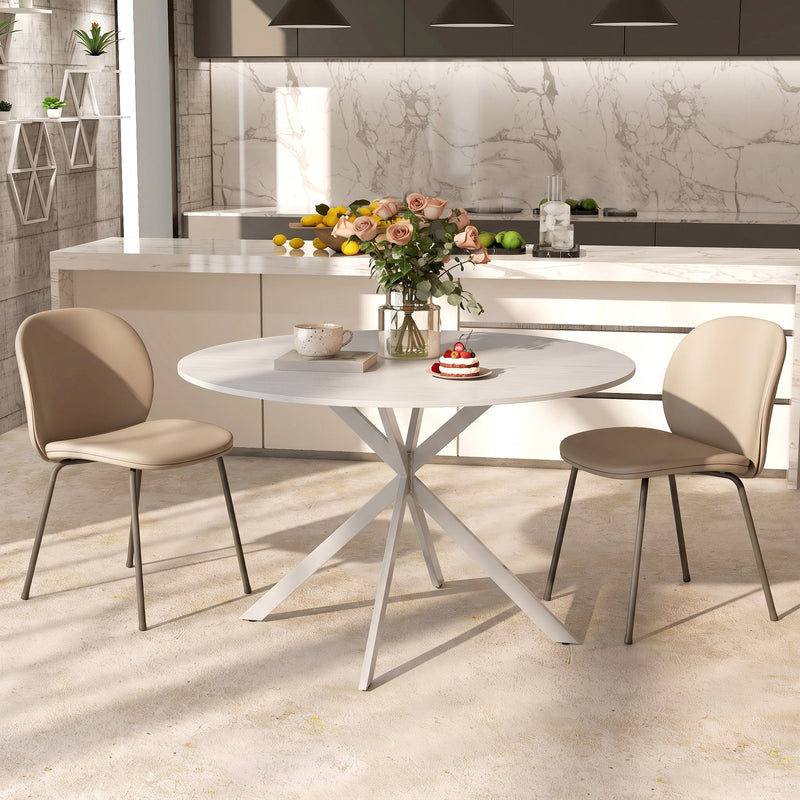Round table in a modern kitchen with two beige chairs and a vase of flowers