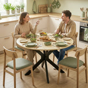 Couple sharing a meal at the round table with green-seated wooden chairs in a corner kitchen
