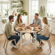 Four adults sharing a meal at the round table in a bright kitchen