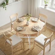 Round table set with plates and flowers for four, seen from above on a woven rug