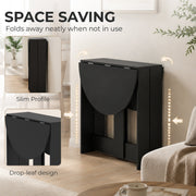 Black folding dining table shown fully folded against a wall