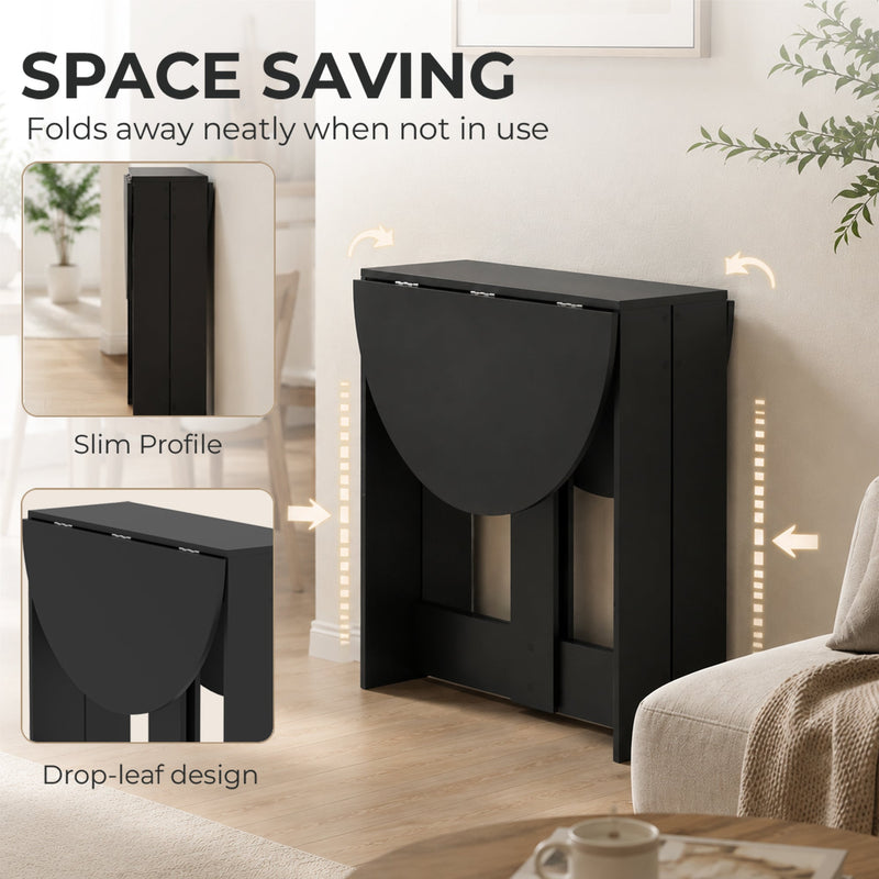 Black folding dining table shown fully folded against a wall