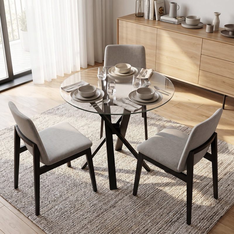 Round glass dining table with light grey chairs beside a wooden sideboard