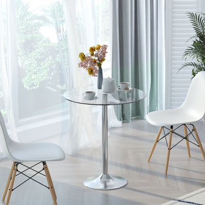 Glass dining table styled by a window with tea cups and a flower vase on top