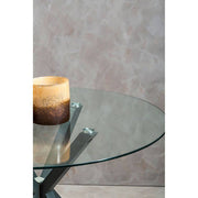 Round glass dining table with grey metal legs, studio shot