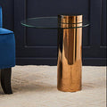Round clear glass side table with rose gold pedestal styled beside a sofa