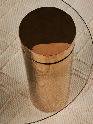 Round glass side table styled with a candle and small floral arrangement