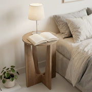 Round side table used as a bedside table with a lamp and an open book