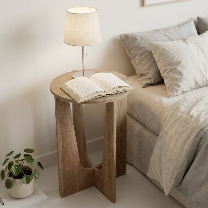 Round side table used as a bedside table with a lamp and an open book