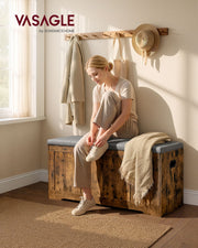 Woman sitting on the rustic brown storage bench with grey cushioned seat in a hallway