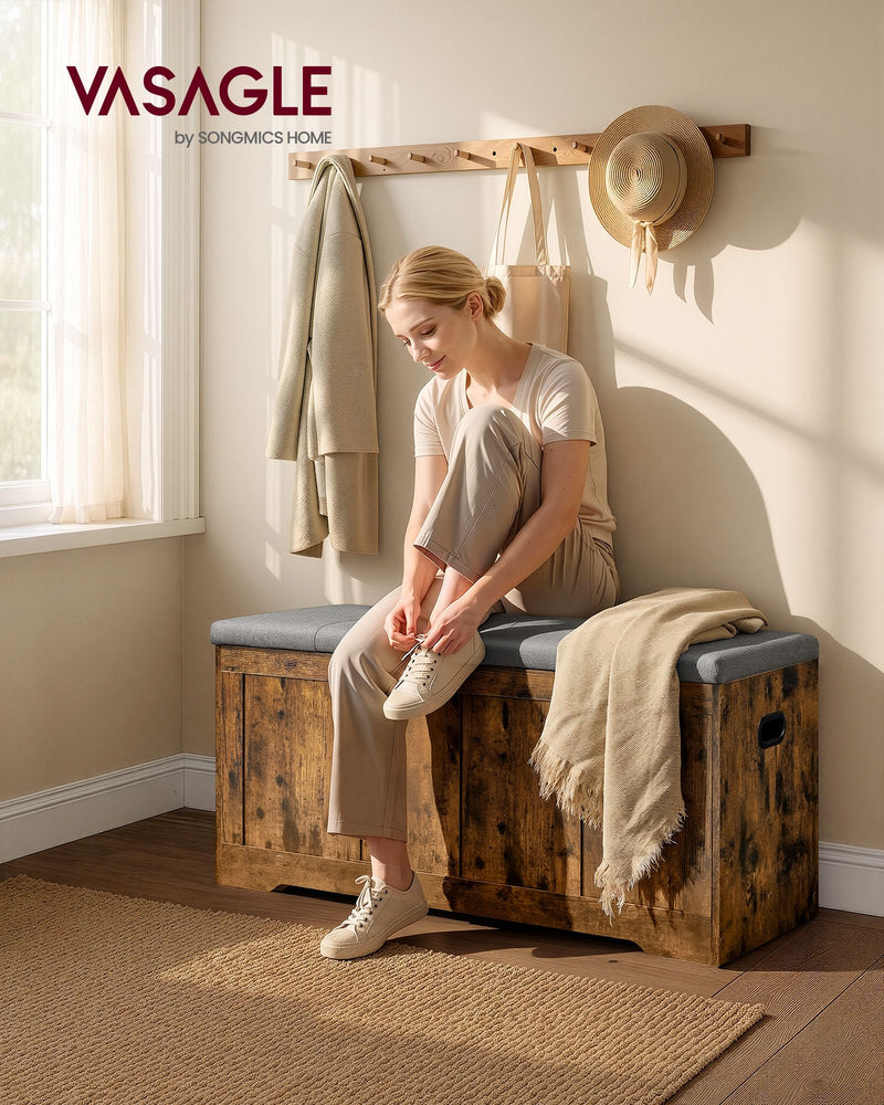 Woman sitting on the rustic brown storage bench with grey cushioned seat in a hallway