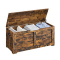 Rustic brown storage chest blanket box open showing folded clothes and pillows inside with a side handle