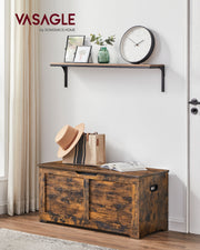 Closed rustic brown storage chest used as an entryway bench below a wall shelf with a hat and bag on top