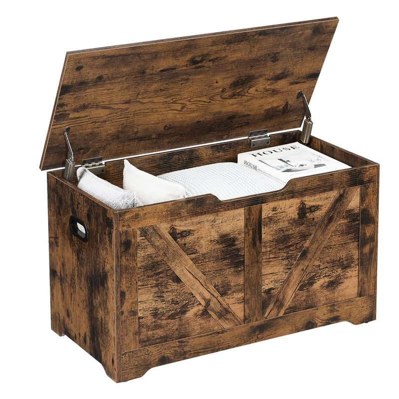 Rustic brown Vasagle storage chest with lid open showing blankets, pillows and a magazine inside