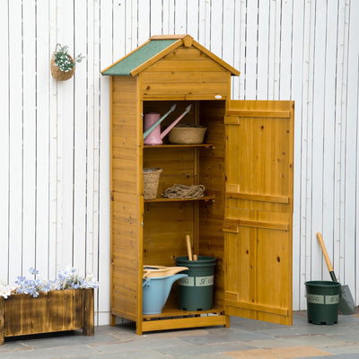 Wooden tool shed against a white fence with the door open showing shelves and plant pots