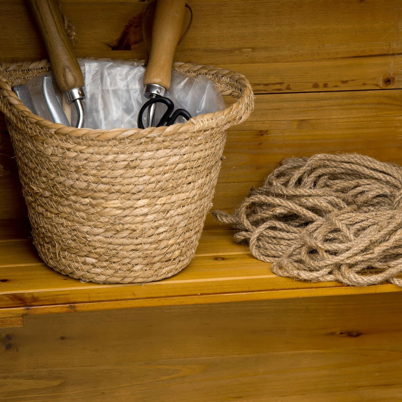 Close-up of a woven basket of hand tools and coiled rope on a wooden shelf inside the shed